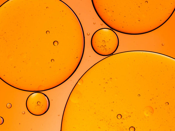Orange liquid cell structures and bubbles symbolizing CoQ10 and bioavailable brain supplements.